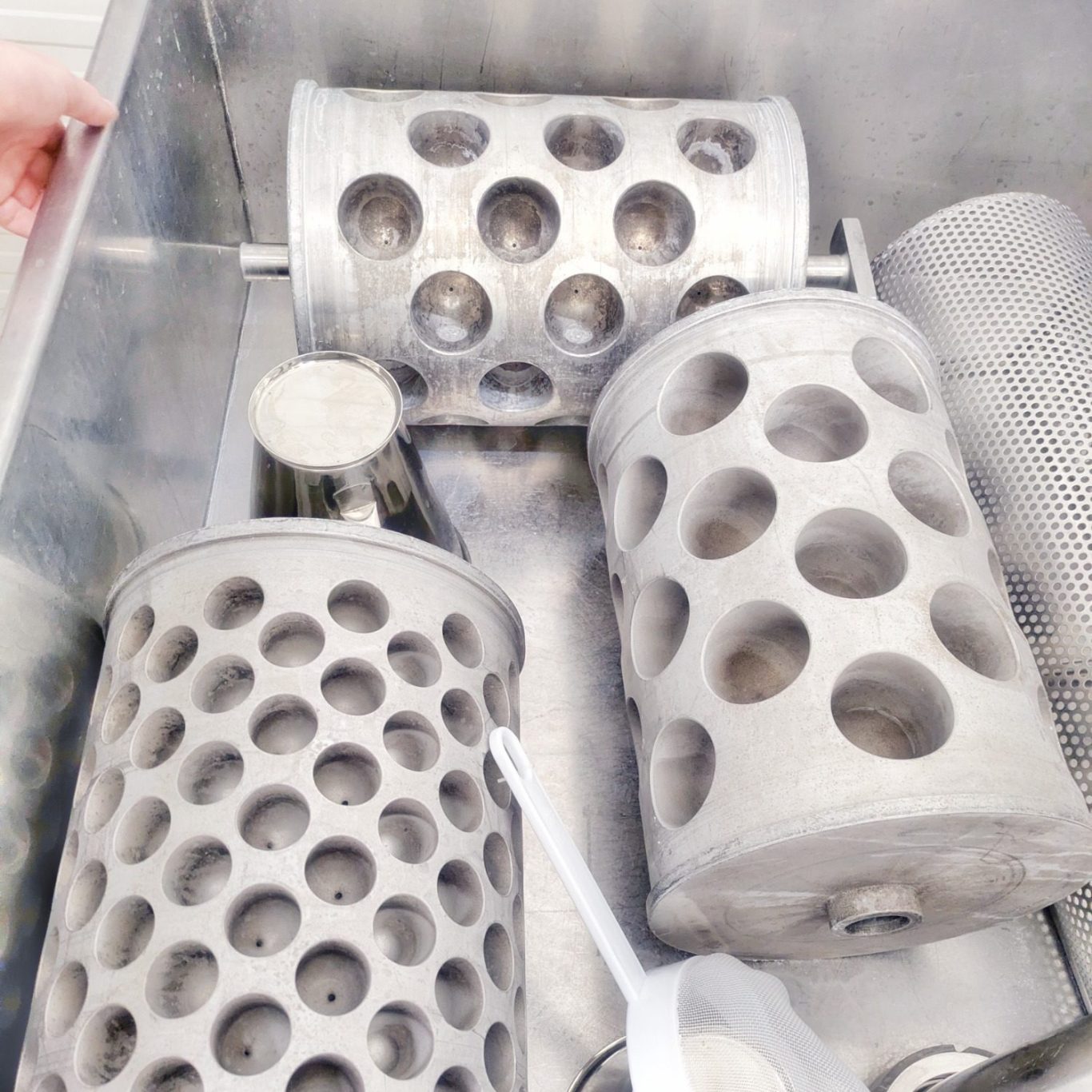 Detailaufnahme der Mozzarellaproduktion: Käseformen liegen in der Käsewanne