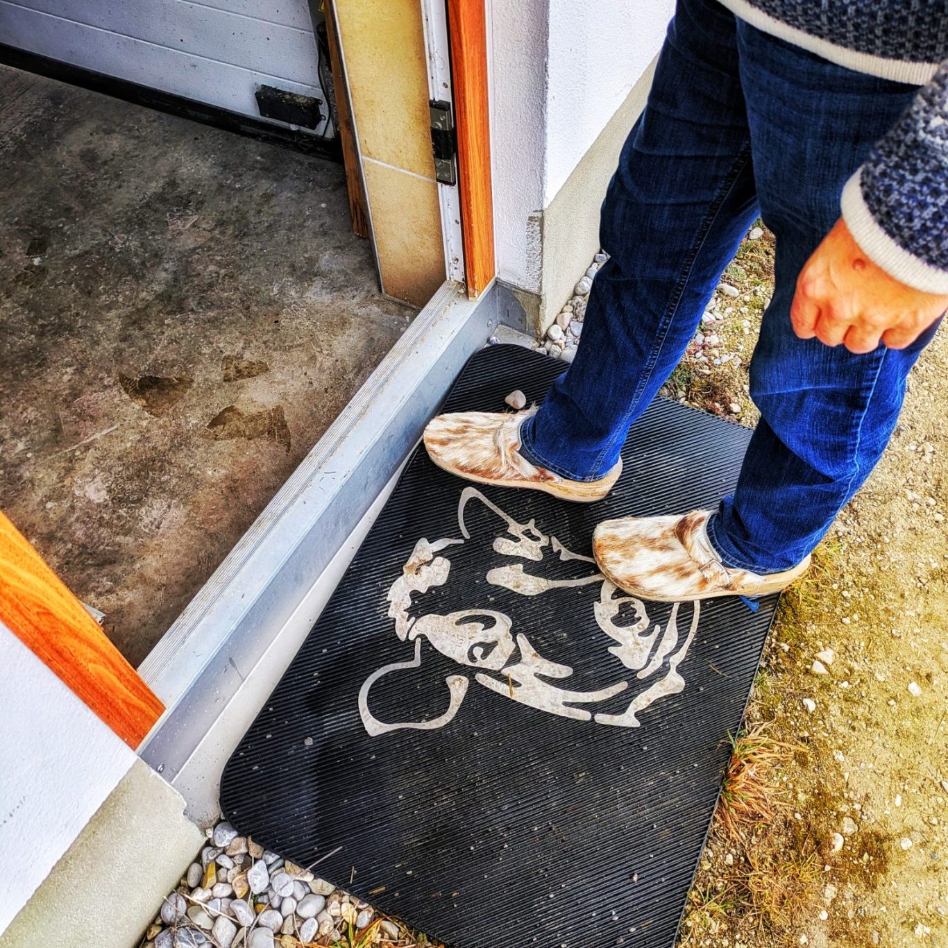 Detailaufnahme von Füßen in Kuhfell-Crocs vor der Eingangstür zum Wandlerhof