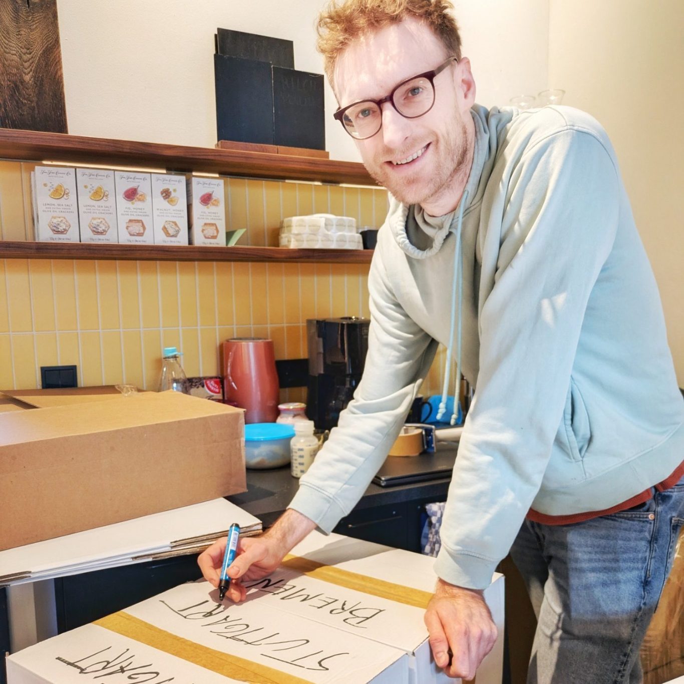 Johannes Kreuels beschriftet ein Versandpaket mit Käse im Verkaufsraum der Münchener Käsemanufaktur in München.