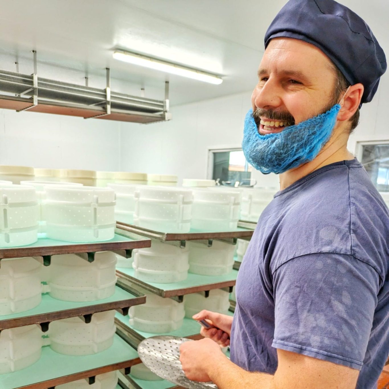 Marc King strahlt mit Pelle à Brie in der Hand in der Käserei der Fen Farm Dairy
