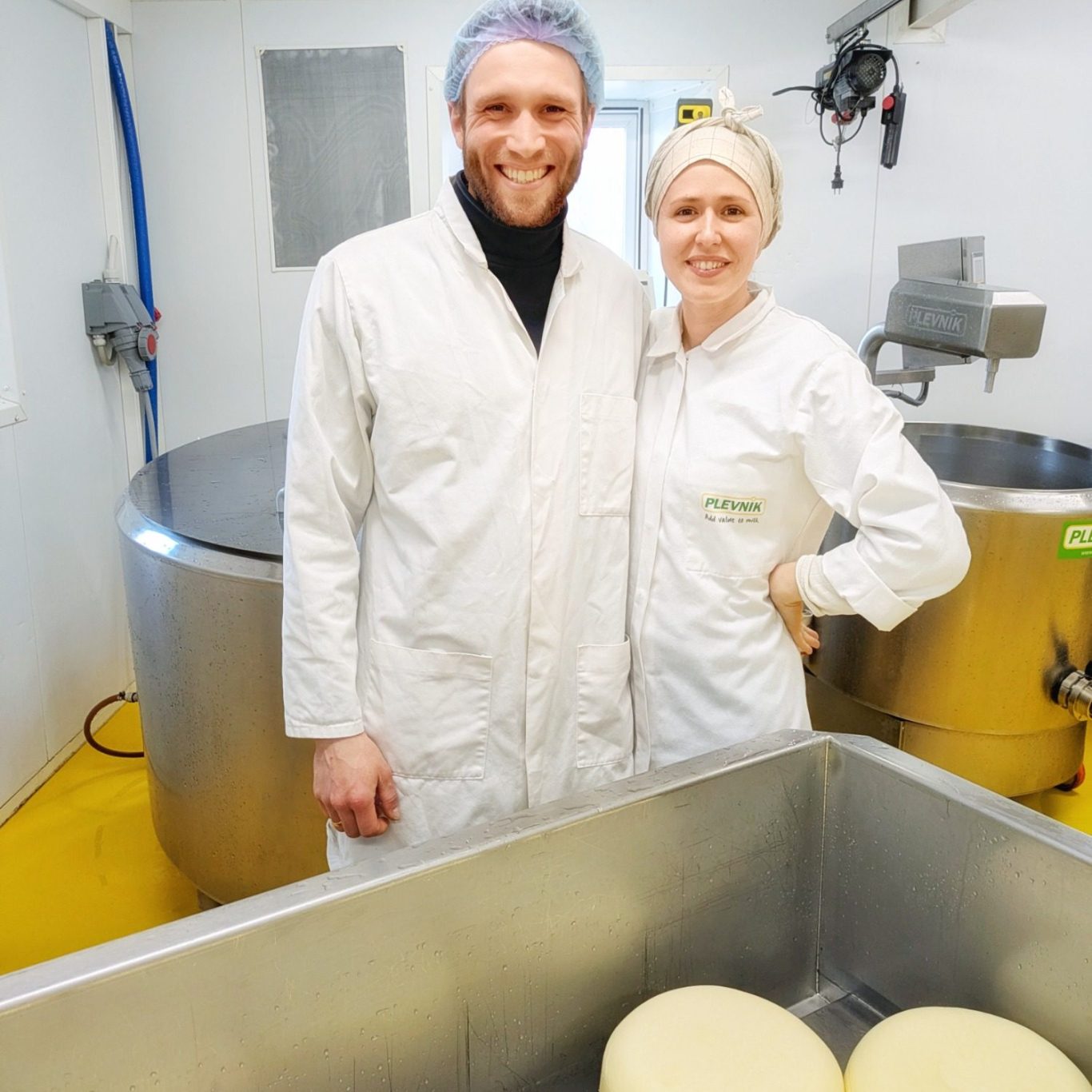 Marie Linea Østergaard und Mikkel Poulsen stehen in der Käserei der Søtofte Gårdmejeri im dänischen Seeland und blicken in die Kamera.