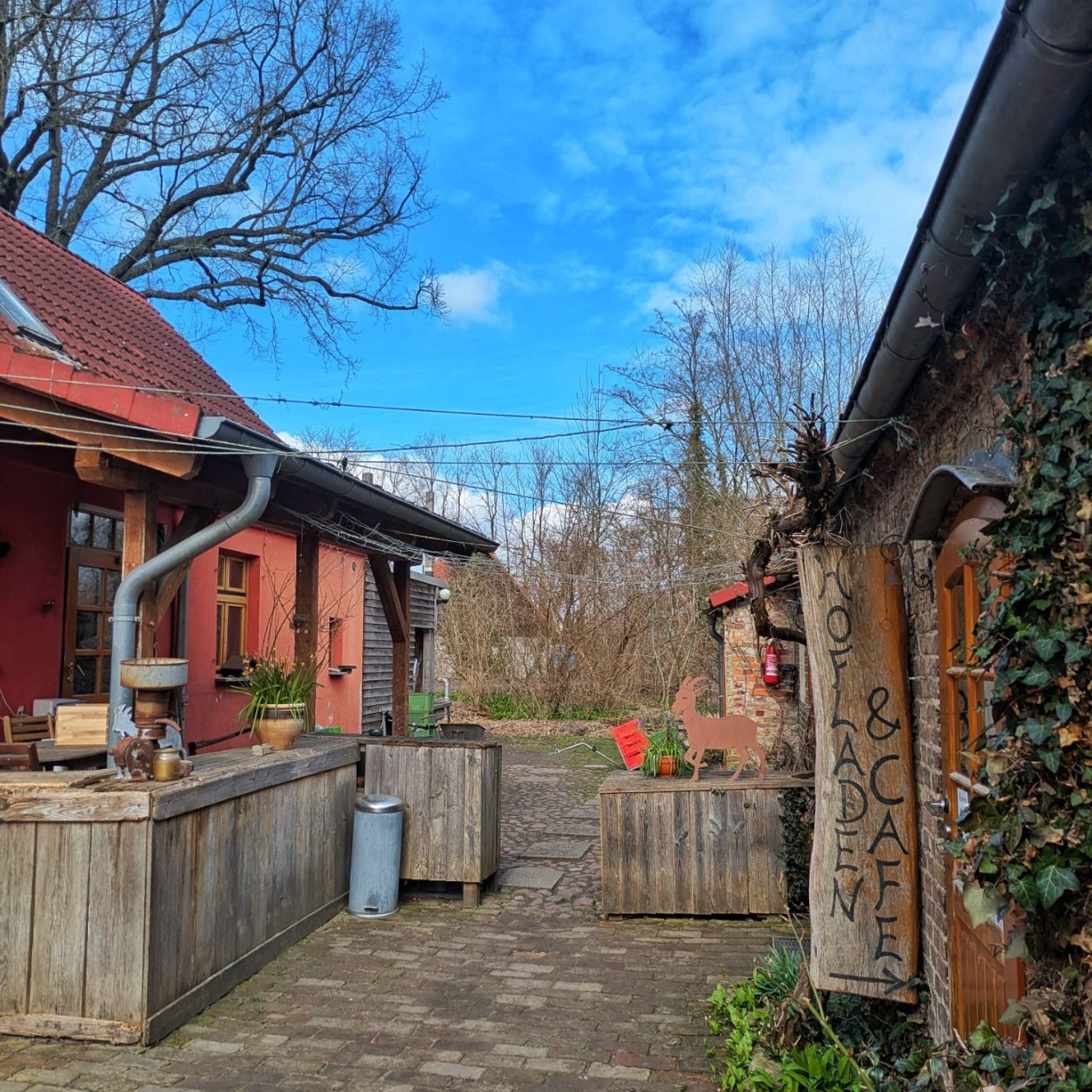 Außenaufnahme des Hofcafés auf dem Karolinenhof bei Sonnenschein, mit rostroten Gebäuden und einladendem Innenhof