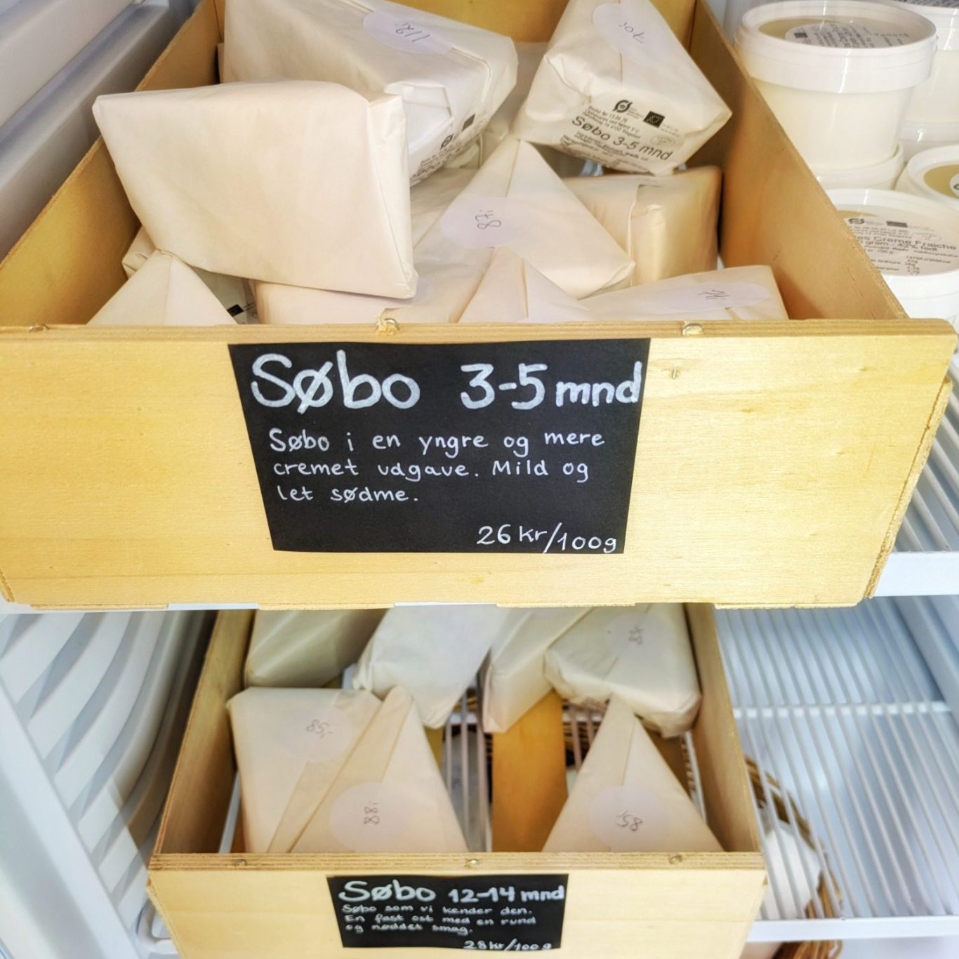 Mehrere verpackte Stücke des Søbo-Käses liegen im Kühlschrank der Søtofte Gårdmejeri und sind bereit für Verkauf oder Auslieferung.