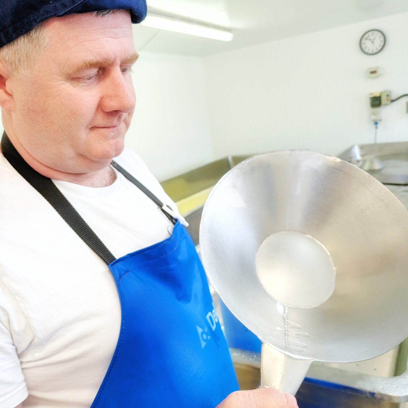 Joe Schneider hält eine selbstgeschärfte Edelstahlkelle im Käsereiraum der Stichelton Dairy