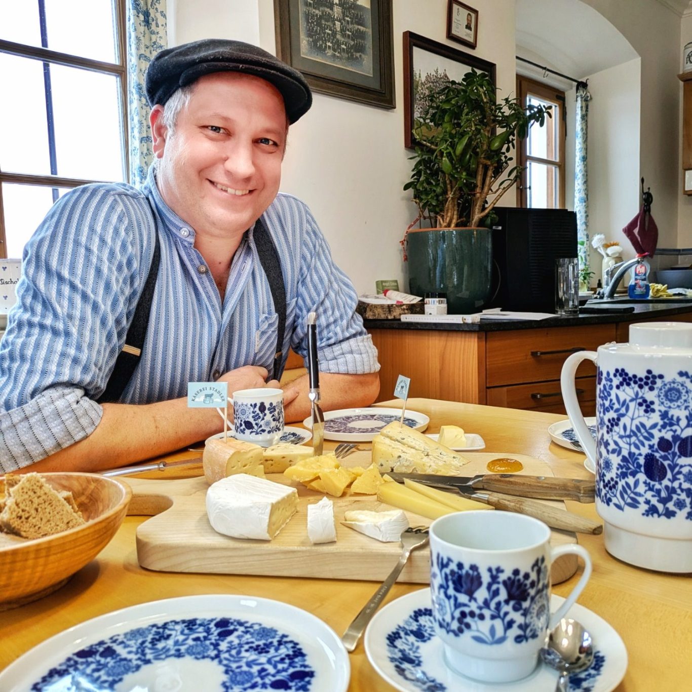 Hubert Stadler steht in seiner Küche neben einem gedeckten Tisch mit Käse und Brot.