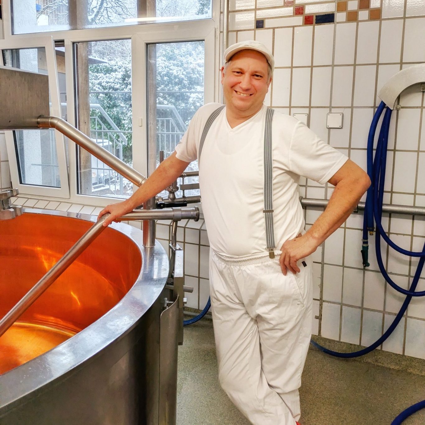 Hubert Stadler steht in der Käserei neben einem großen Kupferkessel.