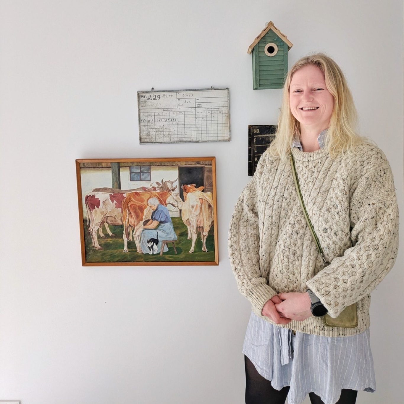 Siri Vilmann steht vor einer dekorierten Wand im Veranstaltungsraum der Øllingegaard Mejeri und lacht in die Kamera