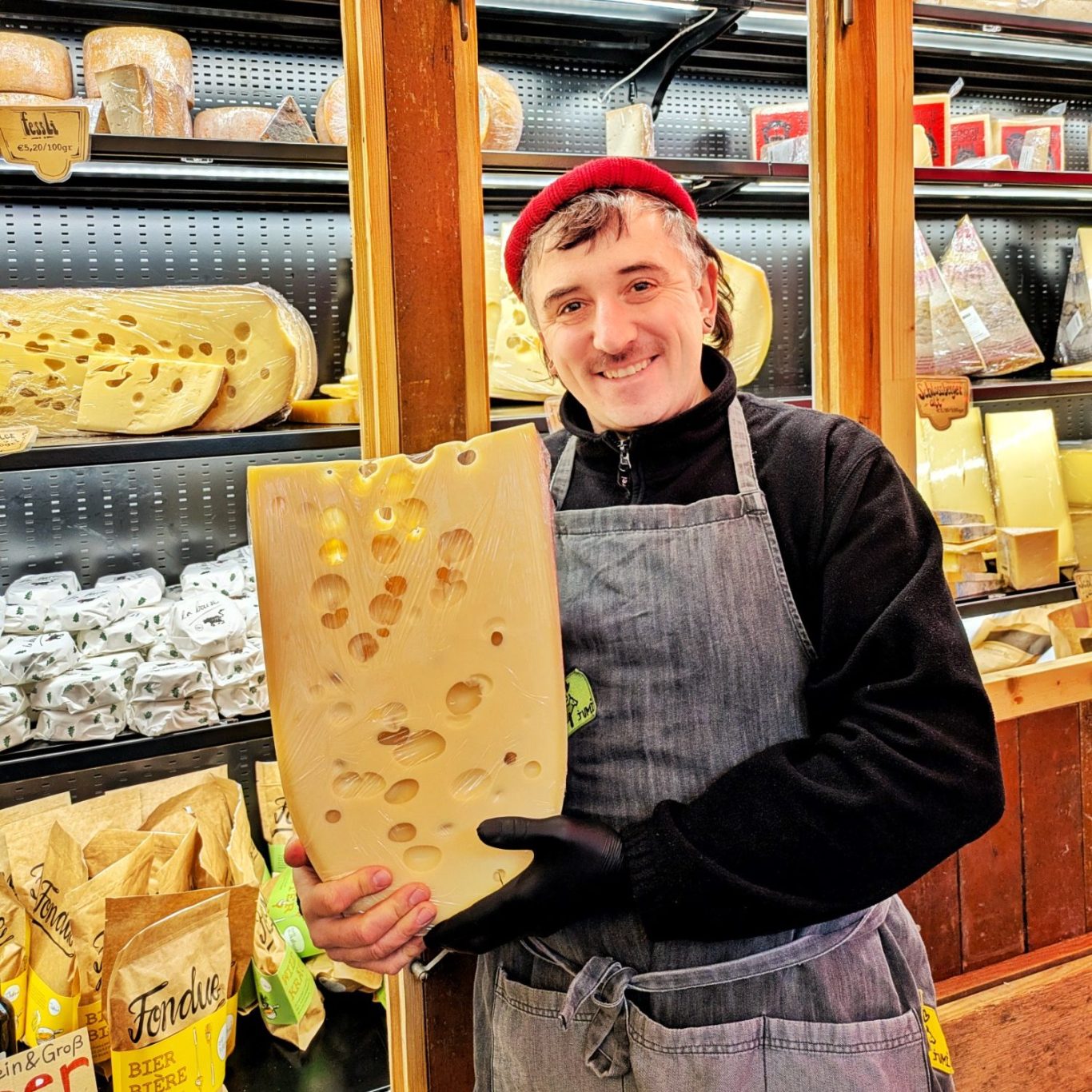 Porträt von Clemens Castan im JUMI-Laden in Wien, der einen Emmentaler in den Händen hält