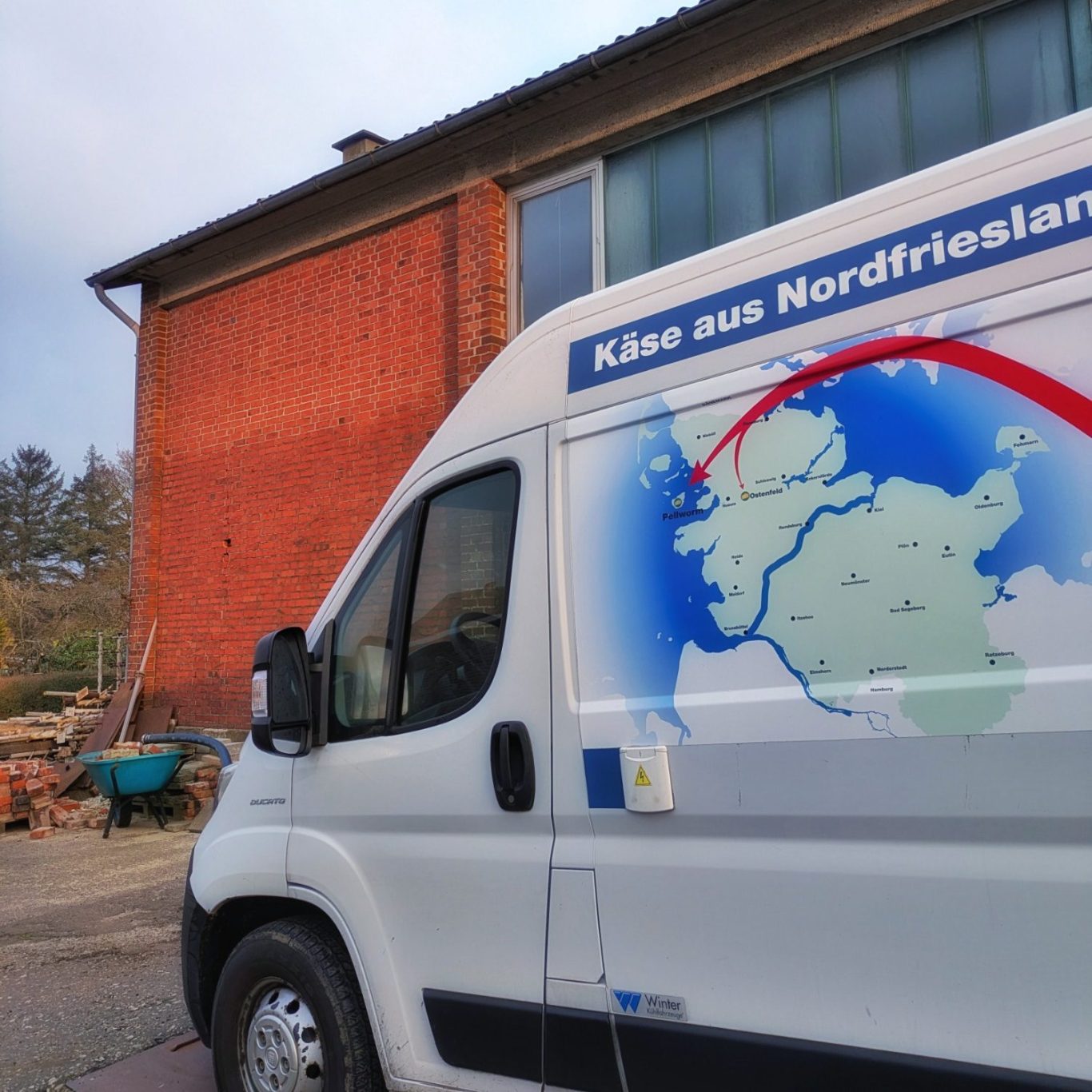 Lieferwagen der Ostenfelder Meierei mit Grafik zu Transportweg nach Pellworm Weiße Lieferwagen mit grafischer Darstellung des Transportwegs der Ostenfelder Meierei zwischen Ostenfeld und Pellworm.